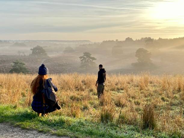 Brunssum,  the Netherlands, -  September 12, 2022. Walking couple enjoy the misty sunrise  in the parkland cold Brunssummerheide in the early morning.