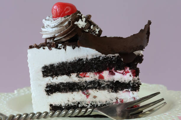 Stock photo showing close-up view of a homemade, luxury, Black Forest gateau displayed against a pink-purple background.