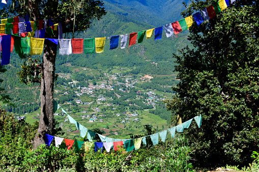 Bhutan, Paro district: upper Paro valley framed by Buddhist prayer flags - view from the Tiger’s Nest trail, leading to the Taktsang monastery located at an altitude of 3120m. Taktsang heritage forest.