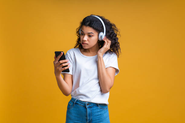 istock Girl concentrated on setting her wireless headphones and browsing music mobile application on her smartphone choosing a song 1423195151