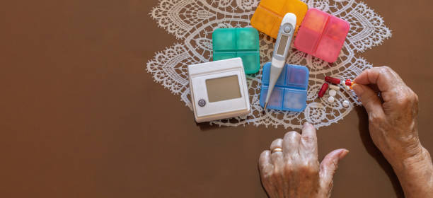血圧計と体温計の隣に丸薬の形で薬を持っている高齢者の手のコピースペースを備えたパノラマ - ipad senior adult 70s adult ストックフォトと画像