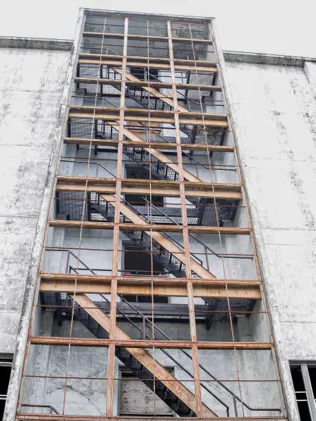 Exterior staircase towers skyward up abandoned industrial building