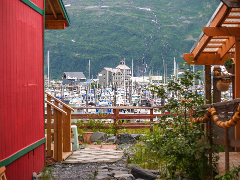 Small waterfall tumbles down mountain background to Whittier industrial and marina area, Alaska, USA
