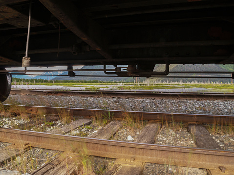 View under railway rolling stock in silhouette to green landscape beyond