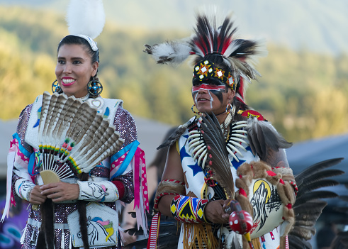 This Powwow took place in Chilliwack, British Columbia on July 29 2017. The powwow is an enthusiastic gathering of First Nations communities, honouring their culture, displaying their regalia,  beating of their drums and dancing. Two dancers pausing between dances.