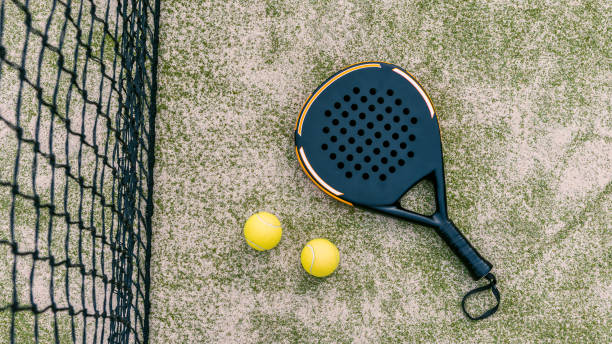vista superior de las bolas amarillas en el suelo cerca de la raqueta de pádel en la pista verde - racket sport fotografías e imágenes de stock