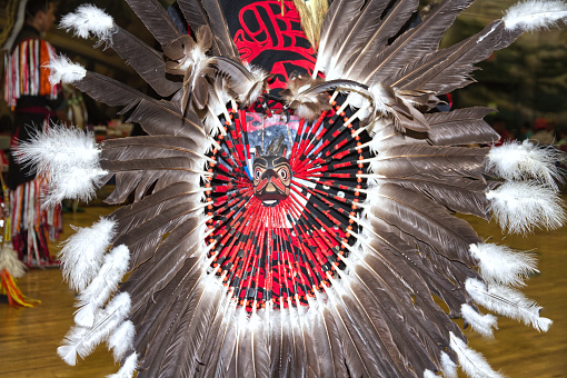 Large, flat, Native American Frame Drum with decorative feathers, and a Hand Carved Flute, and Shaker against a natural stone backdrop.