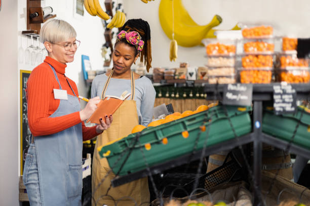 Two female colleagues planning business at the fruits and veggies store stock photo