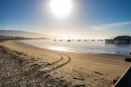 View of Stearn's Wharf from the beach in early morning with ships anchored and sunny bright blue sky