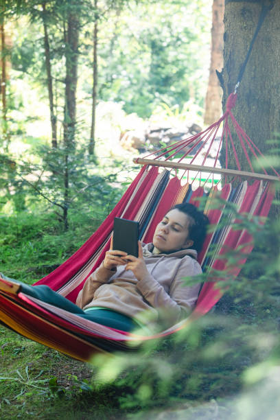 istock woman laying down in hammock reading book 1423215934