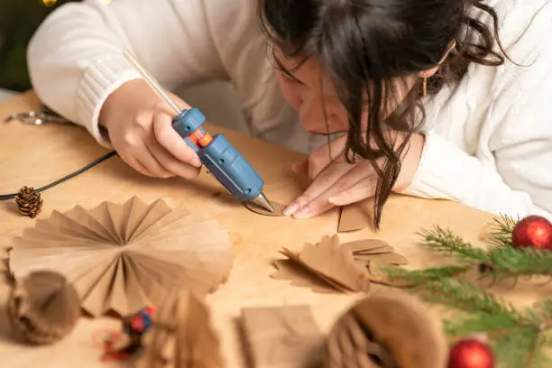 Photo of girl makes Christmas tree decorations out of paper with her own hands. step 3