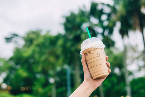 Human hand hold iced coffee, plastic mug.