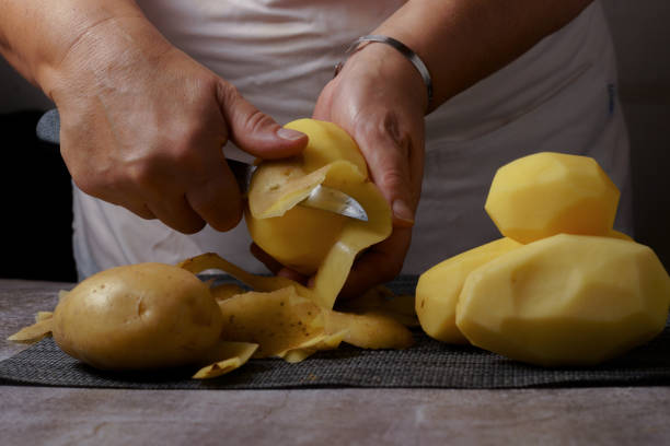 istock woman peeling potatoes with a knife and apron 1423243521