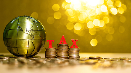 Tax coins and global on shiny golden background.
