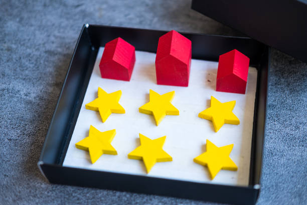 boîte ouverte avec trois maisons rouges avec des étoiles jaunes pour l’évaluation. - loan mortgage document house real estate photos et images de collection