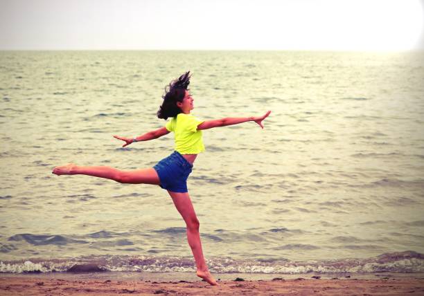 young slender girl jumping on the beach with old toned effect in summer