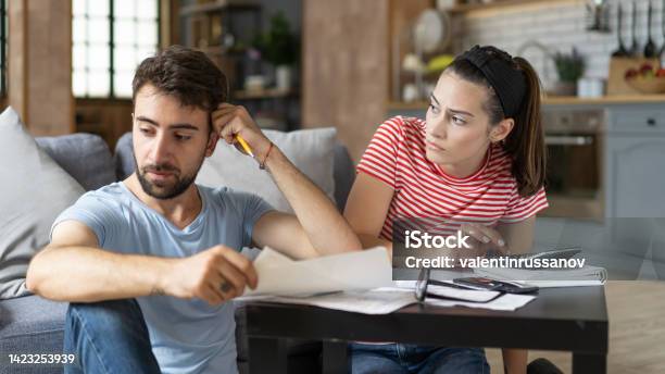 Frustrated Concerned Young Couple Calculating Overspend Budget Doing Paperwork Job At Laptop Talking About Financial Problems Insurance Mortgage Fees Loan Conditions Bankruptcy Economic Inflation Stock Photo - Download Image Now