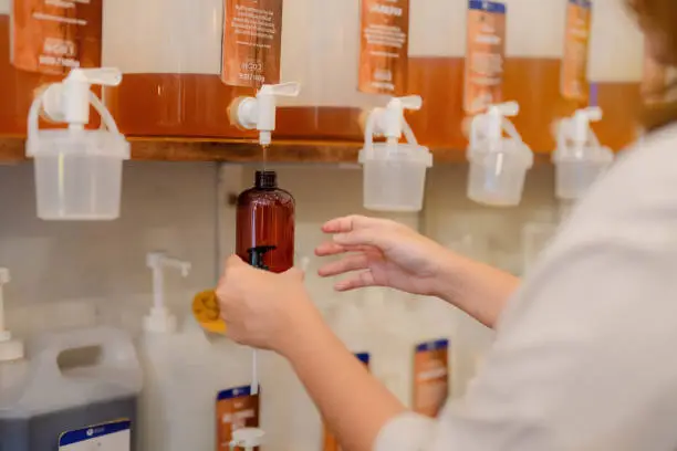 Photo of Woman filling container with cleaning product in plastic free grocery store.