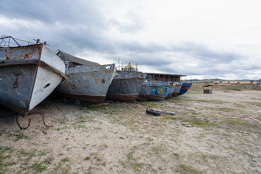 Olhon island, Baikal lake, Russia - September 16 2019: Cemetery of old ships, metal rusty fishing boats on baikal lake.  Stored on a shore of bail lake.
