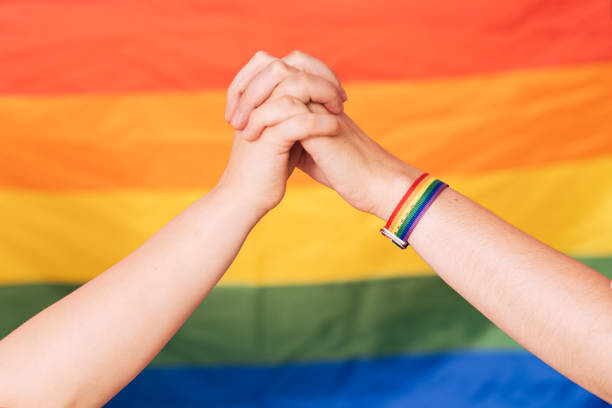 istock Two female hands hold each other against a rainbow background 1423256088