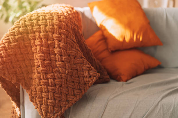 istock Orange pillows and a brown plaid on a gray sofa 1423256706