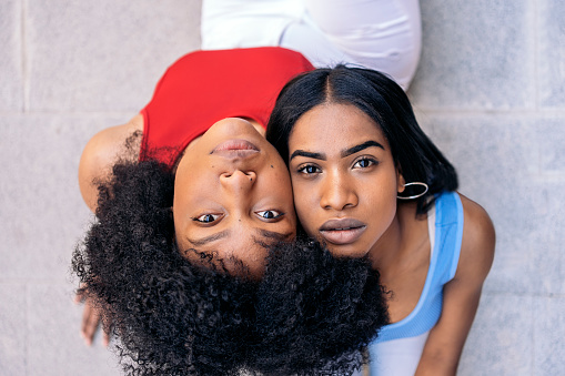 Two young and expressive young black women looking at camera outdoors.