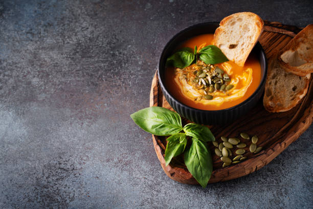 istock Pumpkin soup with bread, seeds and basil leaf on dark background 1423266595