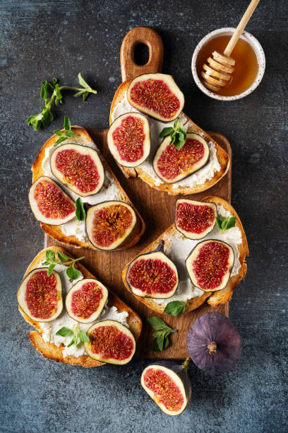 istock Fig bruschetta, bread and cream cheese and fruit on dark background 1423266600