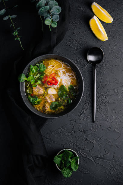 istock Chicken soup with vegetables in black bowl with red pepper 1423267632