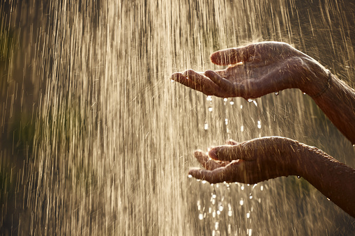 Close up of unrecognizable woman holding her hands under falling water. Copy space.