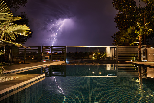 Lightning from a moody sky photographed from a modern backyard.