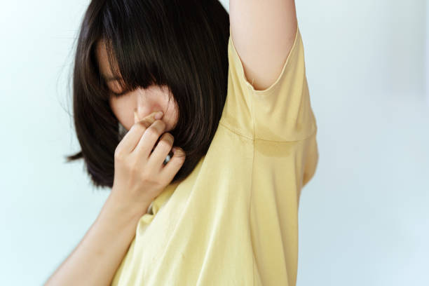 la mujer de la camisa amarilla se cubrió la nariz con las manos porque sudaba en las axilas y tenía mal olor. concepto de atención sanitaria. - deodorant women hygiene body care fotografías e imágenes de stock