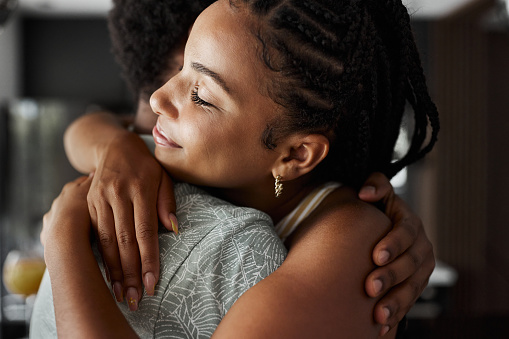 Loving African American woman embracing her boyfriend at home.