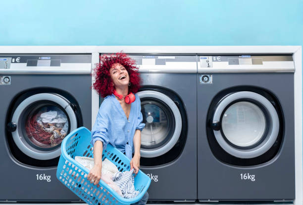 istock A smiling young woman with red afro hair doing laundry in a blue automatic laundromat 1423272633