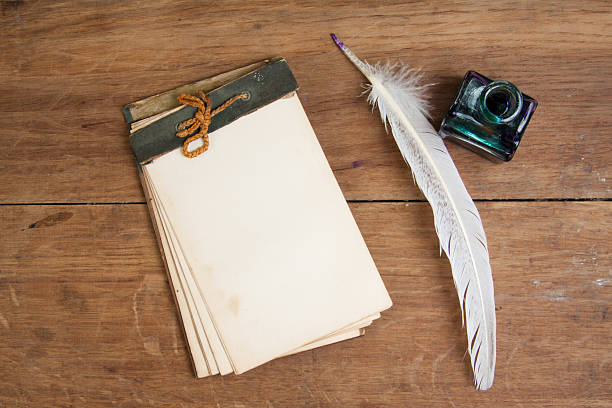 istock Quill ink pen and inkwell, old notepad on wood table 142327385