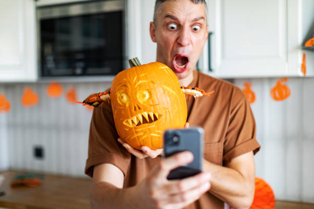 Young adult man making selfie with Halloween pumpkin