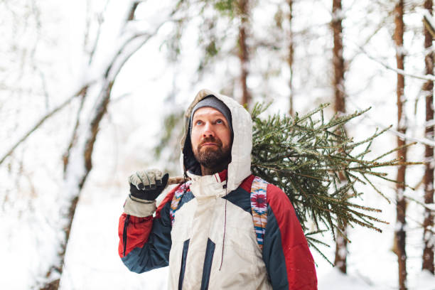 istock Young adult man taking Christmas tree from forest 1423274464