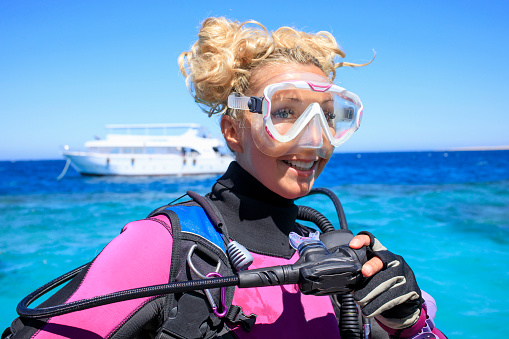 Water sports. Pretty scuba diver, attractive women, ready to go scuba diving or snorkeling.  Long blonde hair, beautiful blue eyes. Sporting women. Beautiful blue sea in the background.