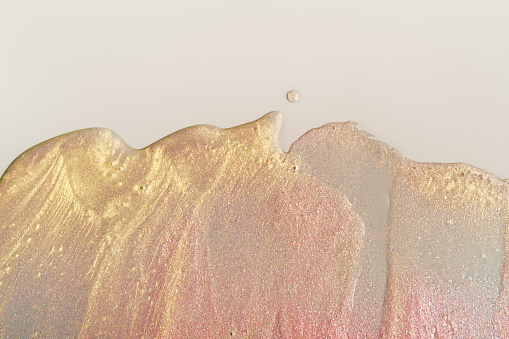 Beauty gel texture with pink and golden particles. Shining highlighter background with brush strokes.