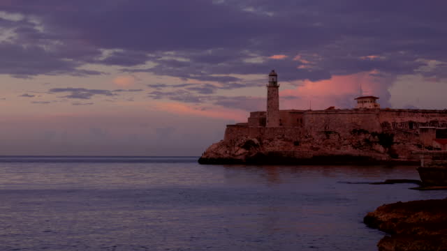 sunset zoom in shot of faro castillo del morro lighthouse in old havana