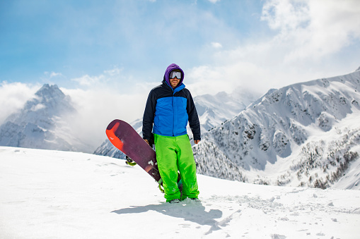 Young adult man snowboarding in mountains