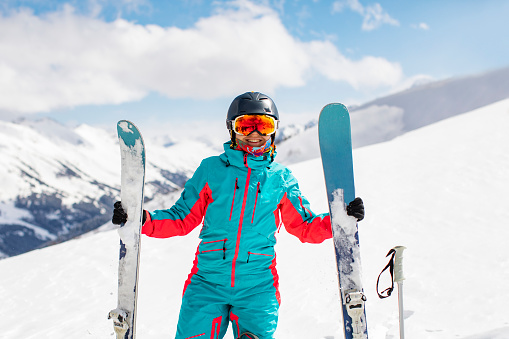 Portrait of beautiful woman with ski and ski suit in winter mountain.
