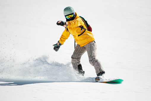 Young adult woman snowboarding in mountains