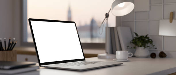 istock close-up, Notebook laptop mockup, table lamp, coffee cup, stationery on the table 1423278138
