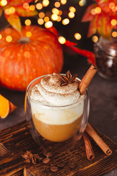 un verre de latte à la citrouille d’automne avec de la crème fouettée et des épices. café à la citrouille et à la cannelle sur fond sombre, lumières bokeh, photo verticale - coffee pumpkin latté autumn photos et images de collection