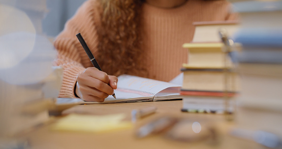 Woman student study, writing and reading education book for an exam or test at school, college or university. Academic girl studying and learning for knowledge  while at a table with notes on paper