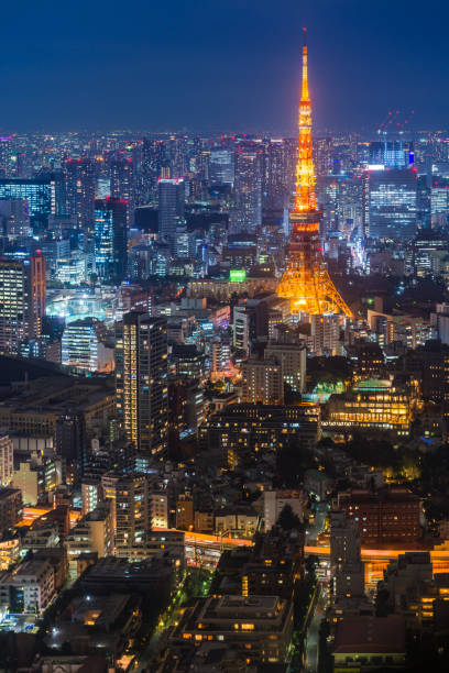 Tokyo Tower illuminated over glittering skyscraper aerial cityscape night Japan The iconic spire of the Tokyo Tower spotlit at dusk above the illuminated urban streets and crowded cityscape of central Tokyo, Japan. tokyo prefecture tokyo tower japan night stock pictures, royalty-free photos & images