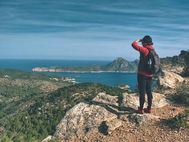 istock Traveler Woman Shadowing Eyes While Watching Blue Sea Bay Within Mountain Single Trail 1423282478