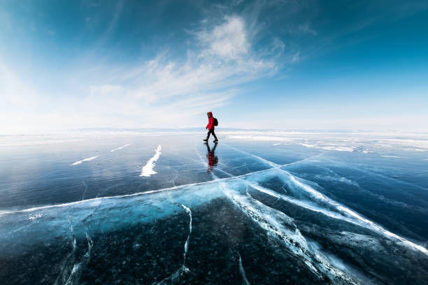 uomo turista che cammina sul ghiaccio del lago baikal. paesaggio invernale del lago baikal, russia - lake baikal lake landscape winter foto e immagini stock