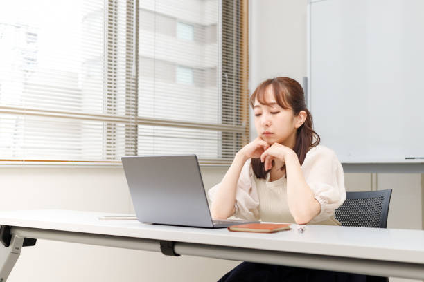 A woman who is having trouble with her job. She is looking at her computer screen with her cheekbones. Attending a seminar or a conference on the Internet. stock photo